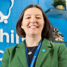 Dr Kathryn Scott, Yorkshire Cancer Research director, standing infront of the Yorkshire Cancer Research logo