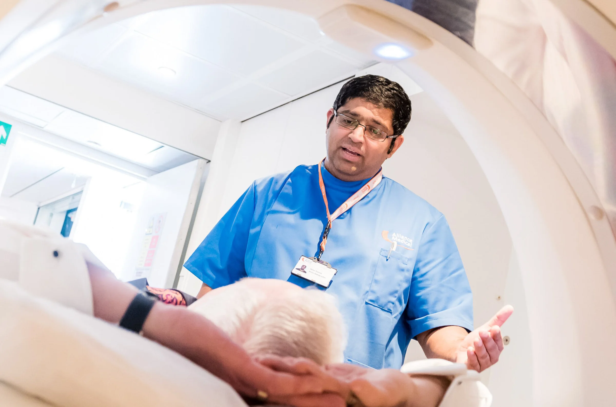 Doctor standing next to a CT scanner talking to patient who is having a scan
