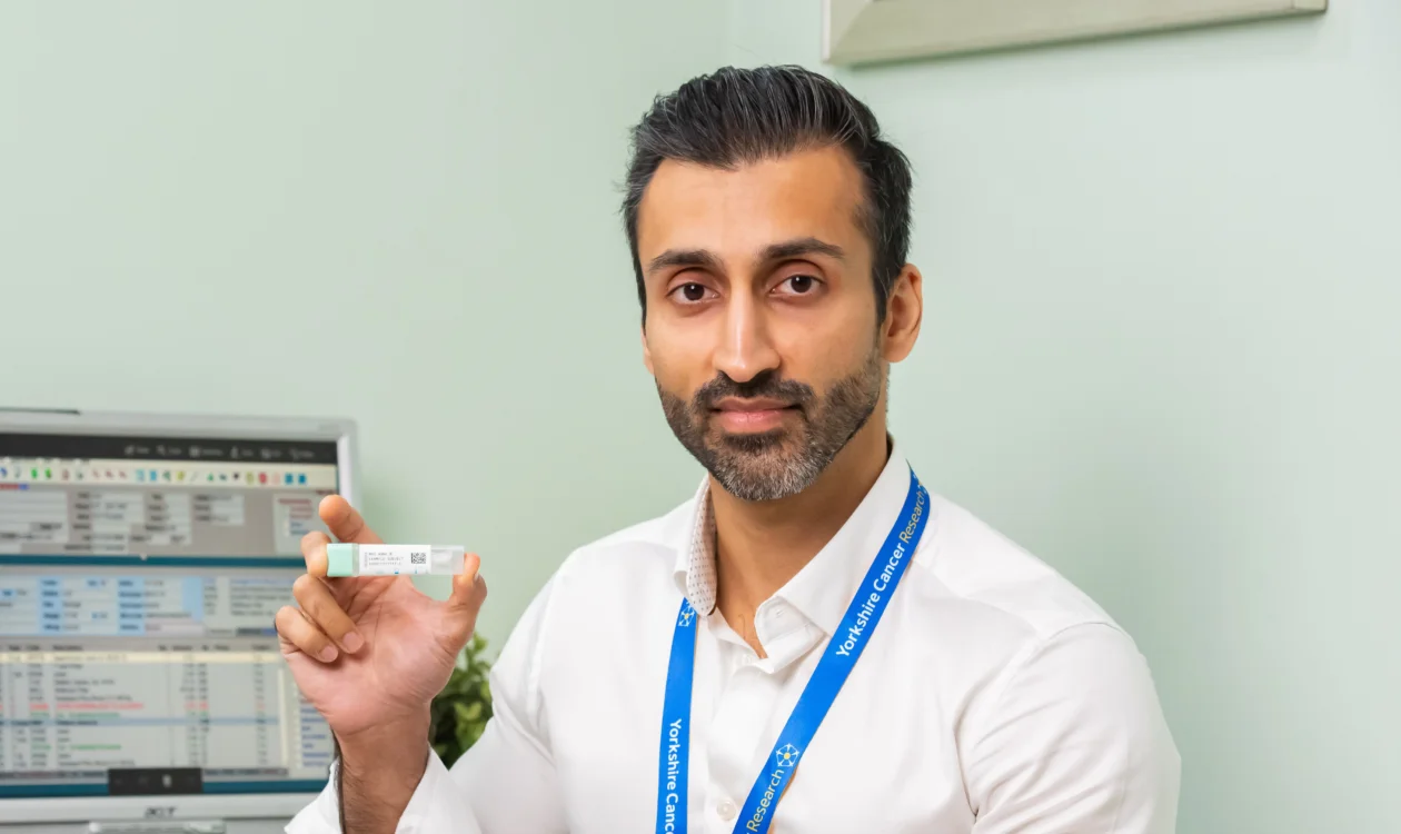 Doctor in Consulting Room holding an NHS bowel cancer screening kit