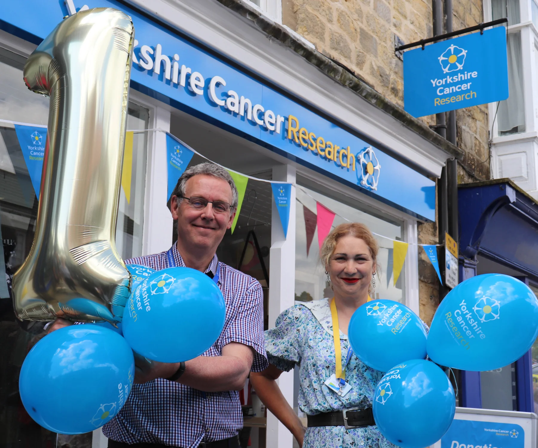 Volunteers stand outside the Pickering charity shop with balloons