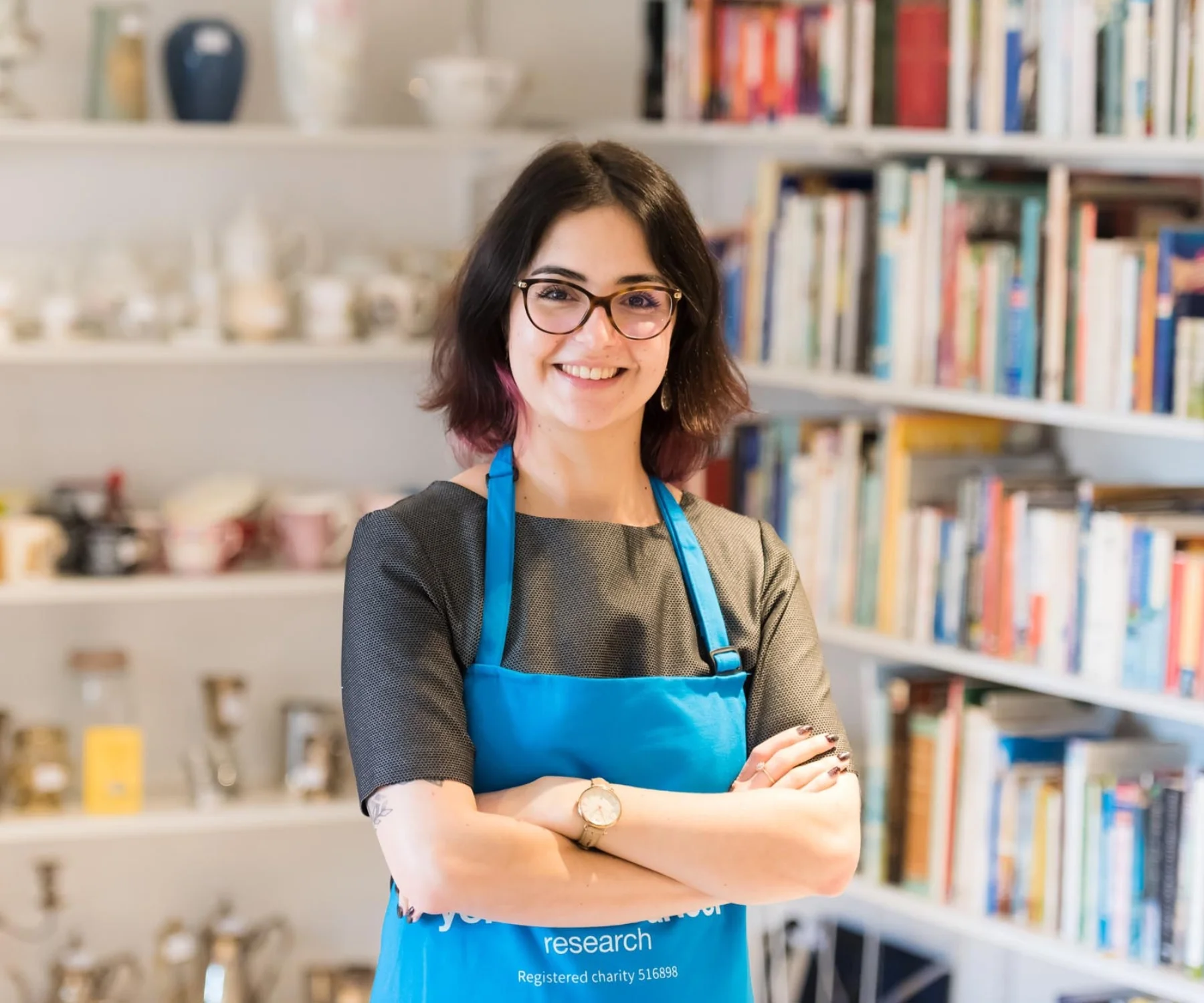 A shop volunteer stands in front of shelves
