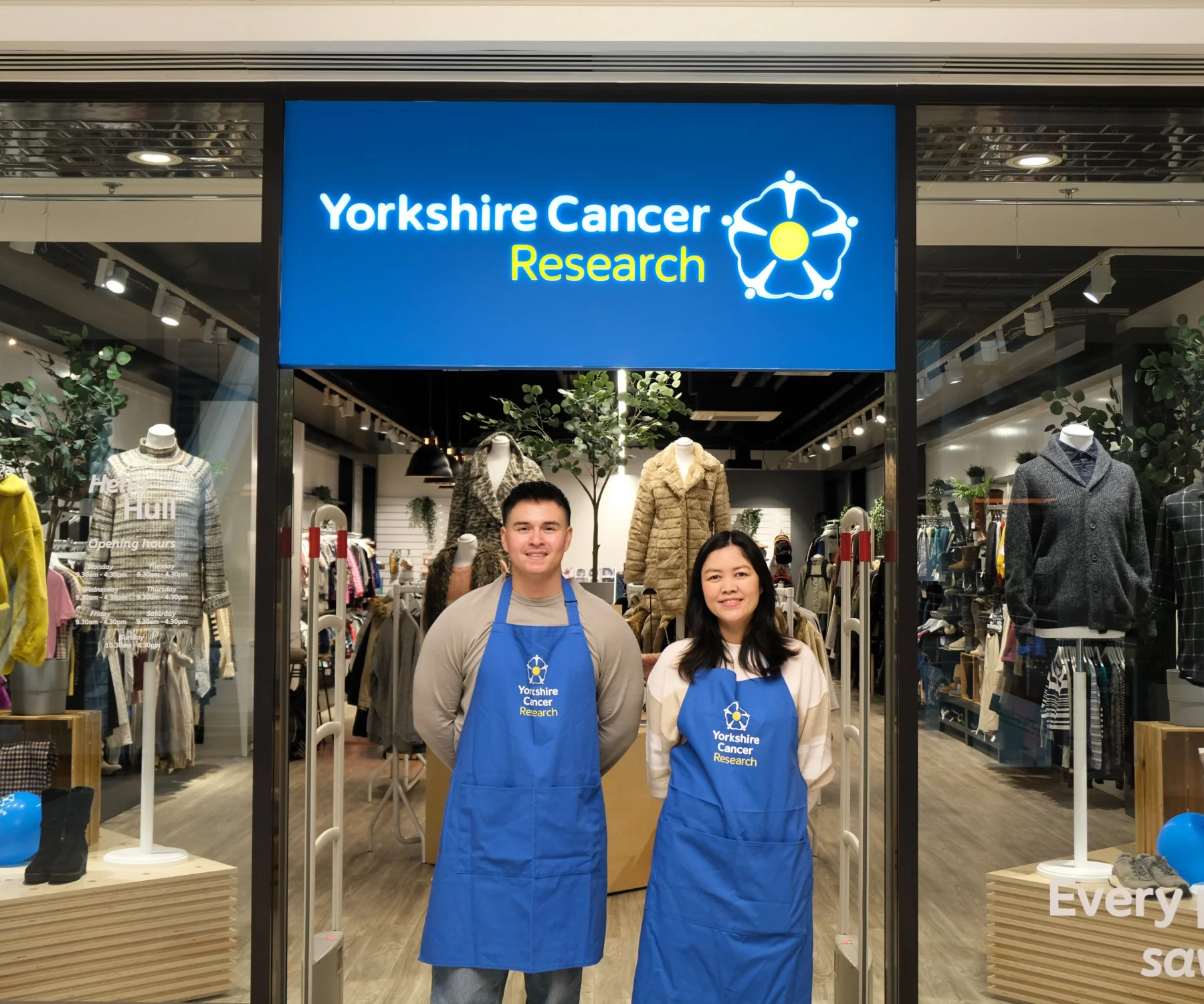 A man and woman stand in front of the Hull Yorkshire Cancer Research shop smiling