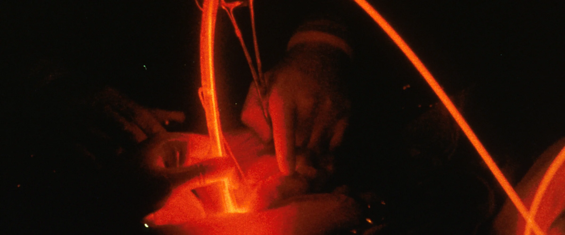 Close-up of hands holding a red-lit optical fibre and surgical scissors